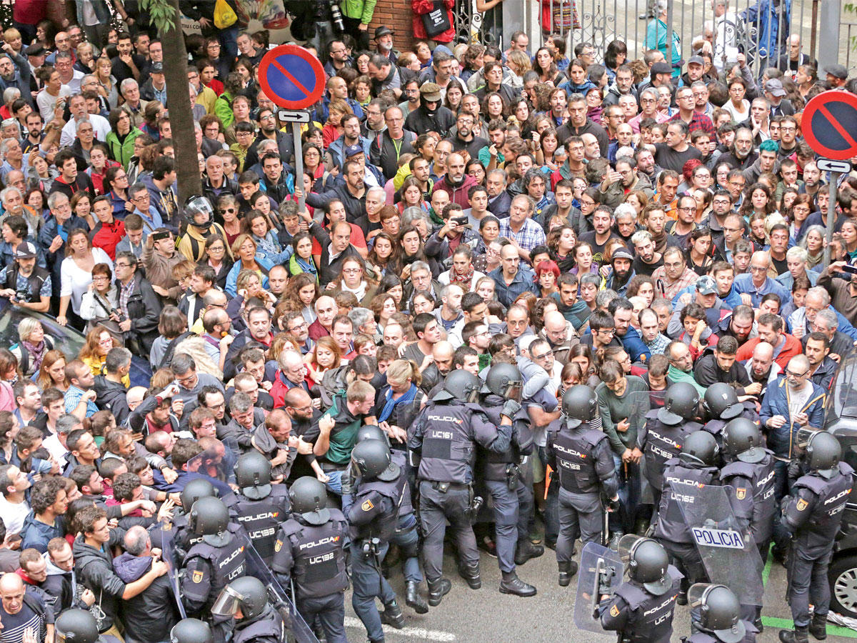 كاتالونيون يحاولون الدخول إلى مركز اقتراع بينما تحاول الشرطة منعهم في برشلونة أمس (اي بي أيه)