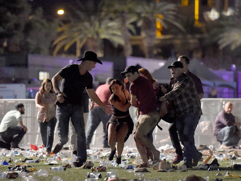 أميركيون ينقلون جريحاً ويفرون من موقع الهجوم في لاس فيغاس أمس (أ ف ب)