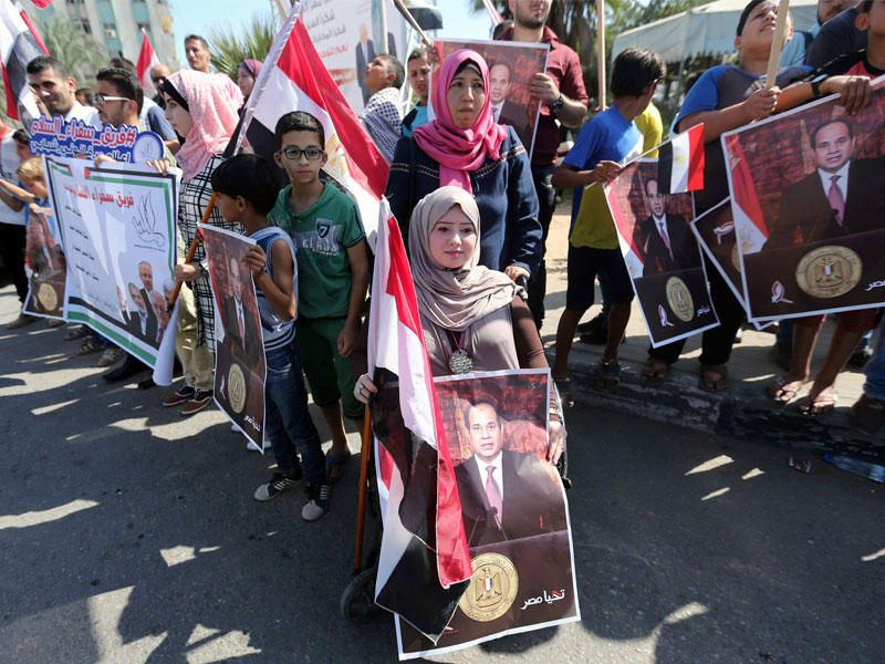 فلسطينيون يرفعون صور السيسي بالتزامن مع انعقاد اجتماع حكومة الوفاق في غزة أمس (رويترز)