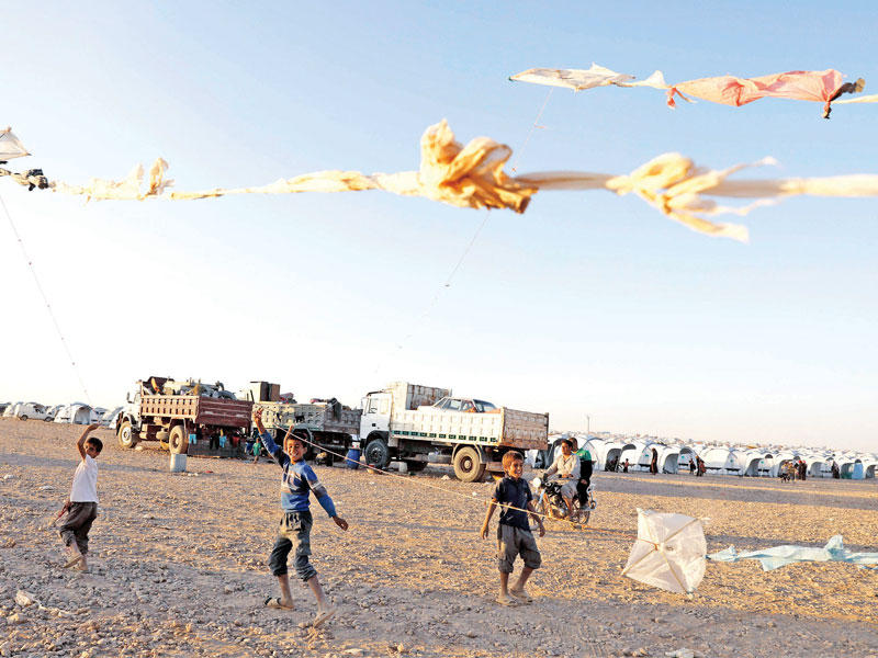 صبية يلعبون بطائرات ورقية داخل مخيم للنازحين في عين عيسى أمس الأول    (رويترز)