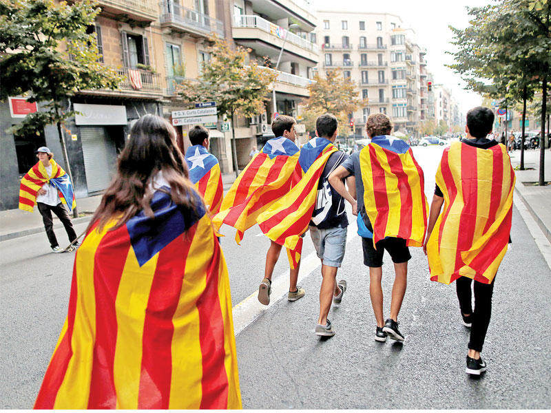 شبان كتالونيون يرتدون أعلام الإقليم في برشلونة أمس (رويترز)