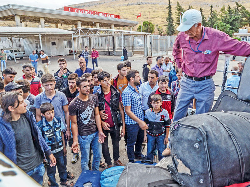 مسن ينزل أمتعة سوريين بعد عبورهم البوابة الحدودية لمعبر باب الهوى إلى الجانب التركي أمس (أ ف ب)