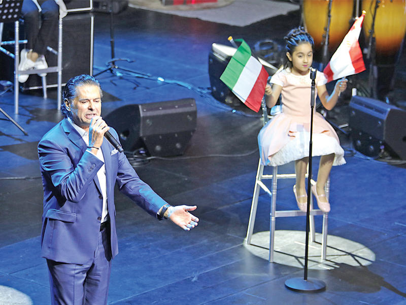 علامة يغني ومعه طفلة على المسرح 