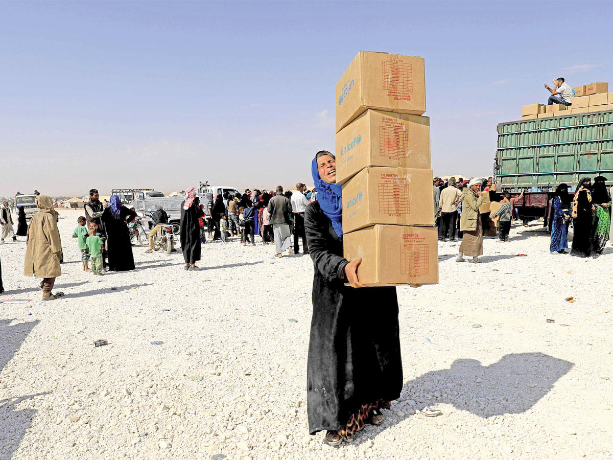 نازحة تحمل مساعدات في مخيم أريشا بالحسكة للفارين من القتال في دير الزور أمس (أ ف ب)