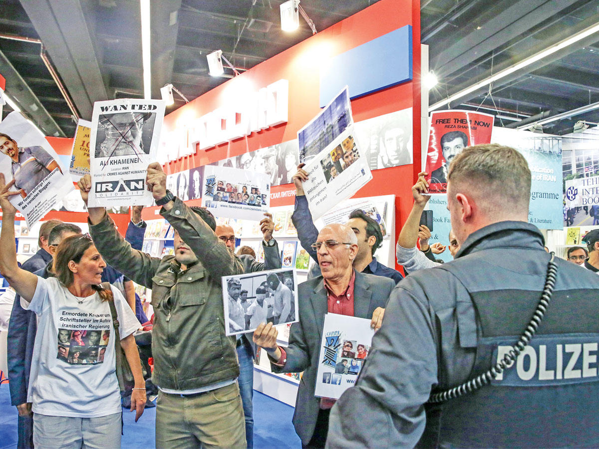 مناهضون للنظام الإيراني يحتجون أمام جناح إيران في معرض فرانكفورت للكتاب بألمانيا أمس الأول  (إي بي إيه)