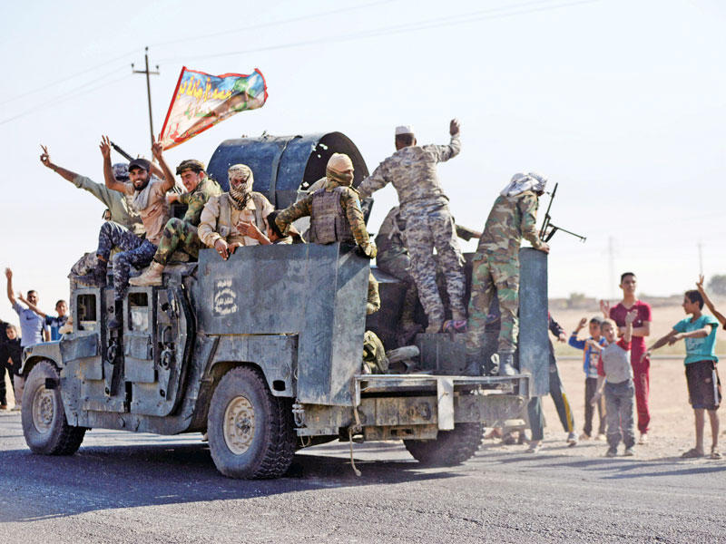 جنود عراقيون على متن شاحنة ترفع راية دينية في كركوك أمس (رويترز)