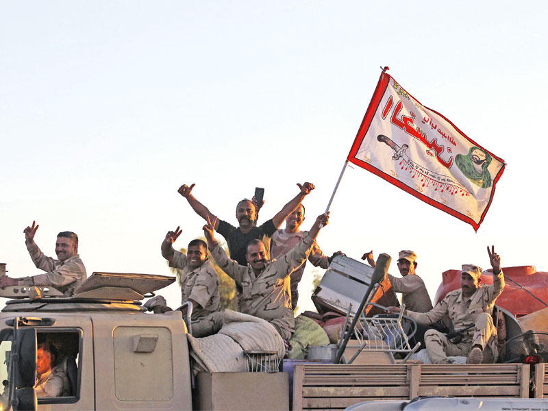 عناصر من «الحشد» على متن شاحنة قال أكراد إنها تحمل ممتلكات استولى عليها المقاتلون الشيعة من مناطق كردية دخلوا إليهاt(أ ف ب)