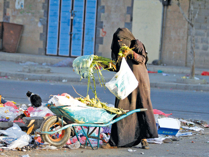 يمنية تبحث في القمامة عما ينفع  في صنعاء أمس (رويترز)