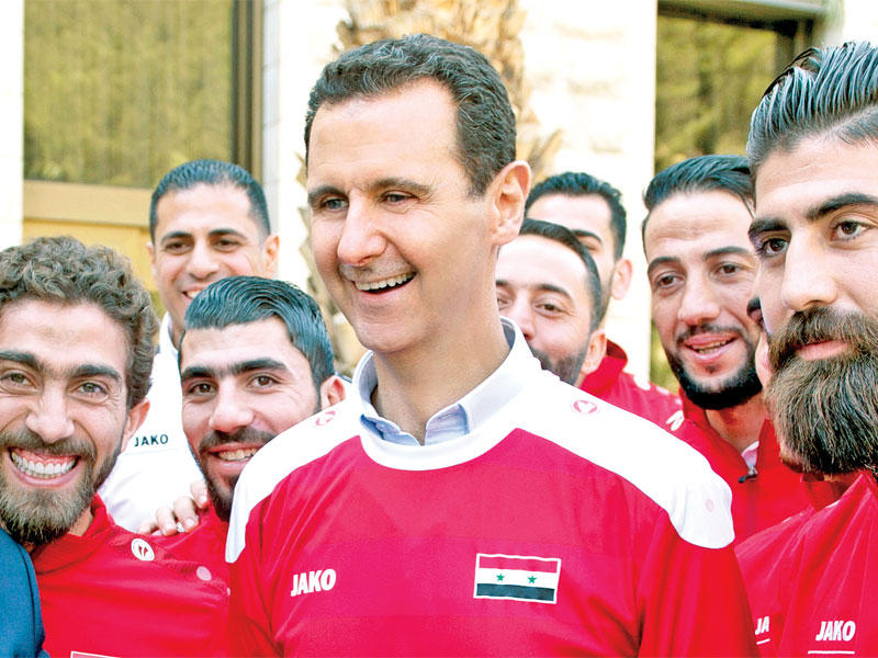 الأسد مرتدياً زي منتخب كرة القدم خلاله استقباله أعضاء الفريق بدمشق أمس (أ ف ب)