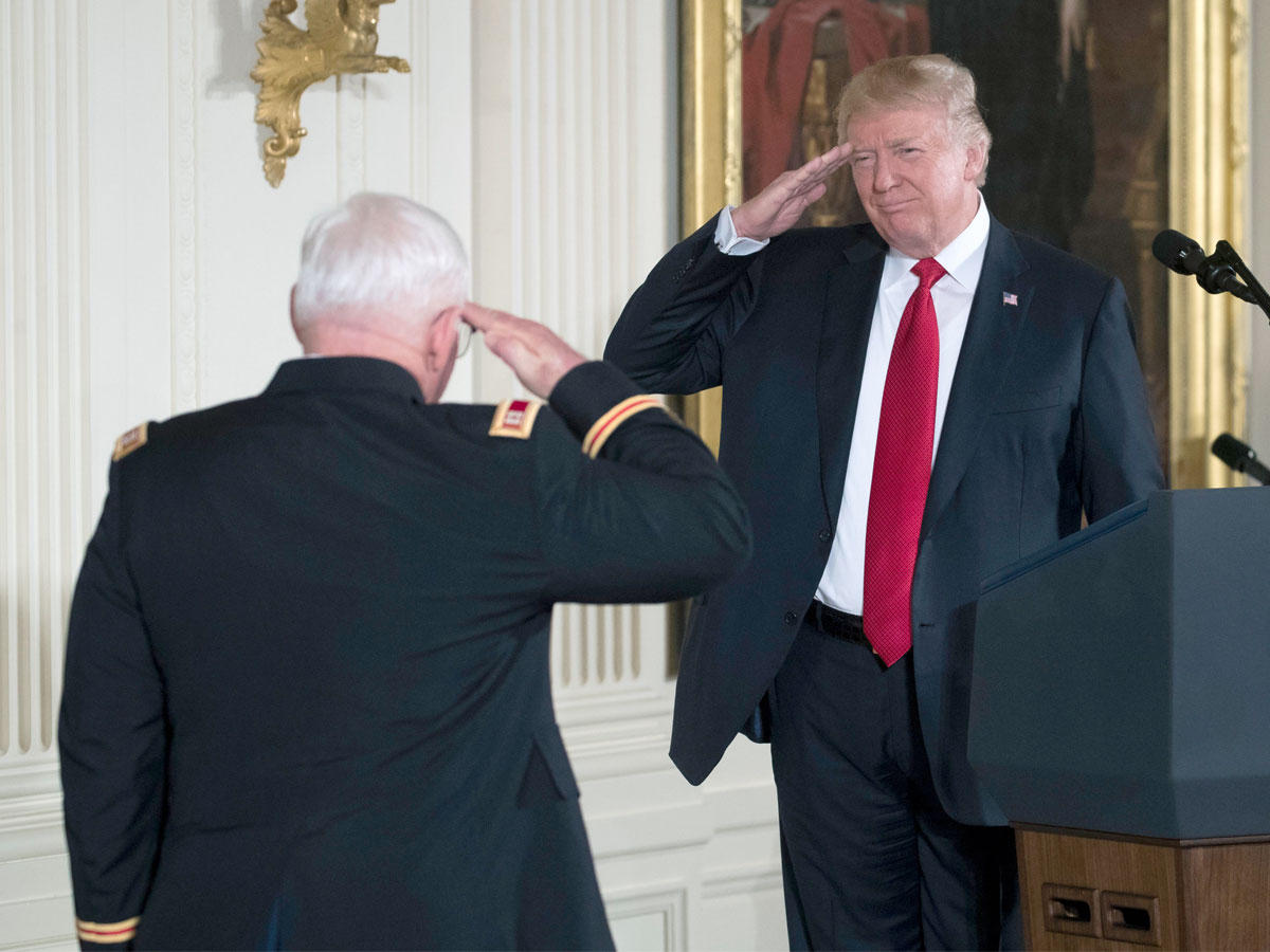 ترامب قبل تقليده جنرالاً أميركياً قاتل بحرب فيتنام ميدالية في البيت الأبيض أمس (إي بي أيه)