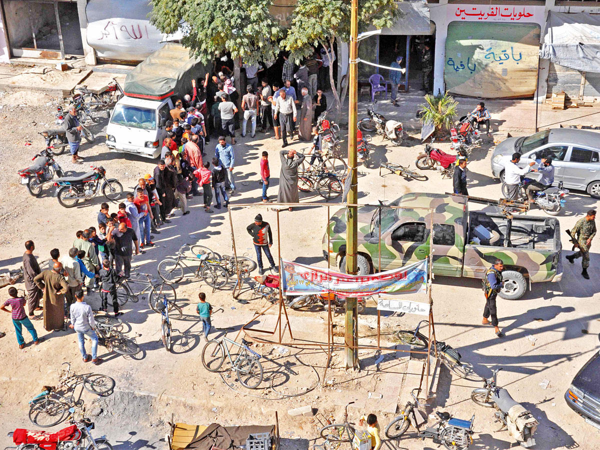 سوريون يصطفون أمس للحصول على مساعدات غذائية من قوات الأسد في بلدة القريتين بحمص التي خرج منها «داعش» قبل أيام  (أ ف ب)