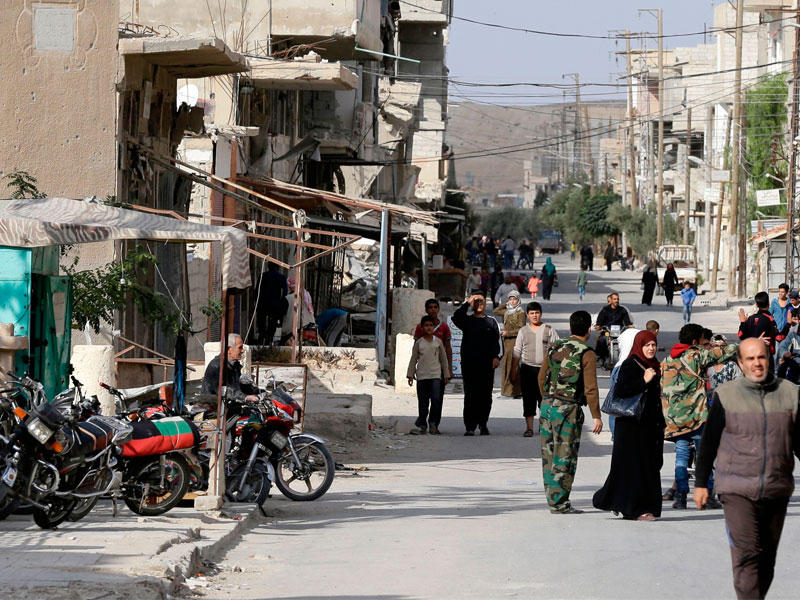 سوريون في أحد شوارع بلدة القريتين بمحافظة حمص أمس الأول (أ ف ب)