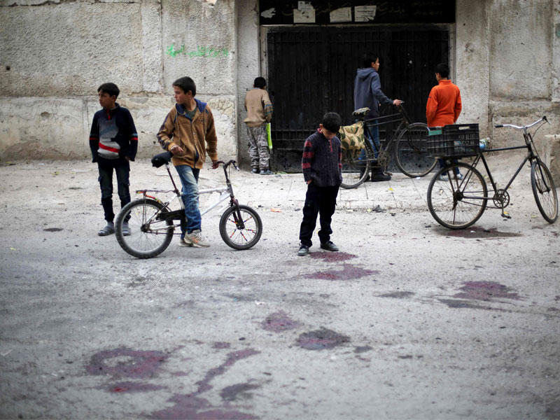 الأطفال السوريون يقفون في مسرح ملطخ بالدماء لقصف قتل فيه تلاميذ المدارس