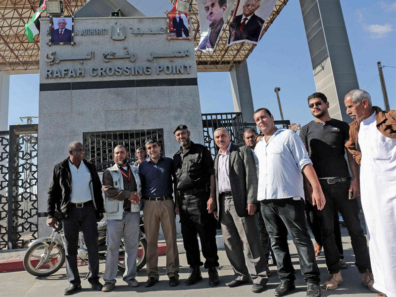 مسؤولو السلطة الفلسطينية وعناصر «حماس» عند معبر رفح الفاصل بين قطاع غزة ومصر أمس (أ ف ب)