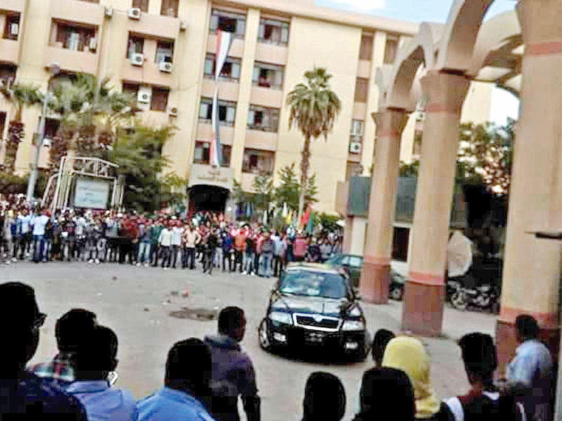 شهدت جامعة الفيوم يوم الأربعاء الماضي مشاجرة عنيفة بين أفراد الأمن الإداري وعضو البرلمان عن دائرة مركز سنورس، منجود الهواري، عقب صفعه مشرفة الأمن على وجهها، بسبب منعها نجلته من دخول الجامعة، وهي الواقعة التي أحدثت أصداء واسعة بعد انتشار مقطع فيديو يحطّم فيه طلاب سيارة النائب.وفي الصورة، تجمّع طلابي يحاصر سيارة الهواري ويحطمها.