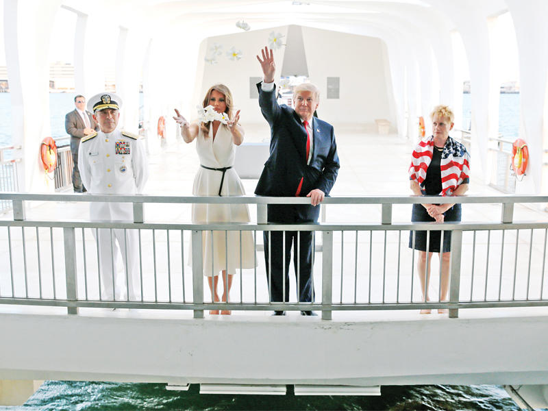 ترامب وزوجته ميلانيا يلقيان الزهور في مياه النصب التذكاري للسفينة الأميركية أريزونا التي أغرقتها اليابان أثناء الحرب العالمية الثانية   (رويترز)