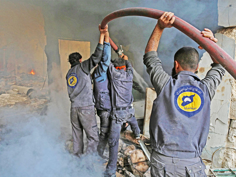 أعضاء الخوذ البيضاء يحاولون إخماد حريق اندلع بعد غارة نظامية على حرستا في غوطة دمشق أمس (أ ف ب)