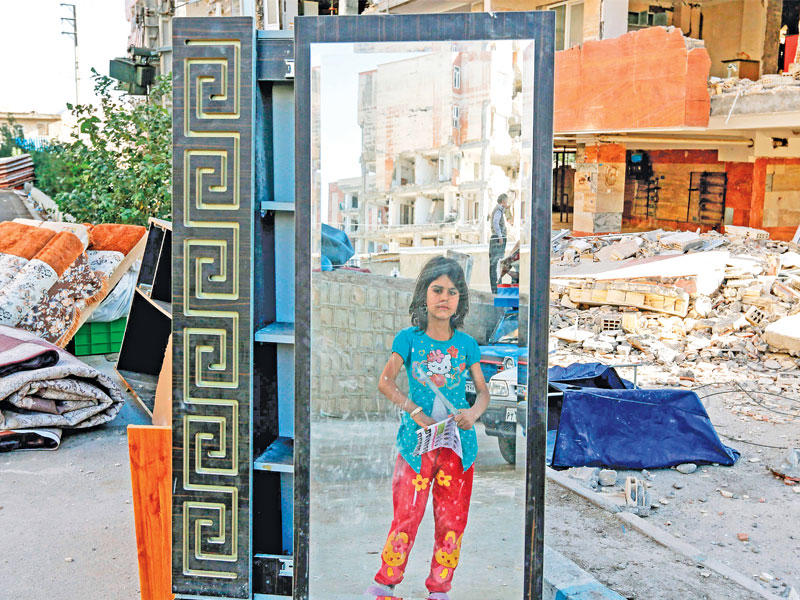 فتاة إيرانية أمام مرآة في أحد شوارع سربول الذهب غرب محافظة كرمنشاه غرب إيران والتي قتل فيها اكثر من 200 شخص في الزلزال (أ ف ب)n