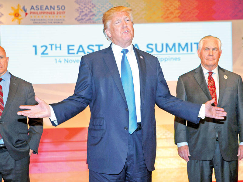 ترامب متوسطاً تيلرسون ومستشار الأمن القومي هربرت ماكماستر قبل مغادرته مانيلا عائدا إلى واشنطن أمس (رويترز)n