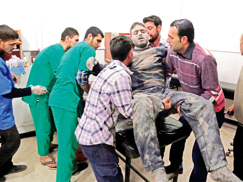 مسعفون سوريون يحملون مصاباً لعلاجه في المستشفى بالغوطة الشرقية (أ ف ب)