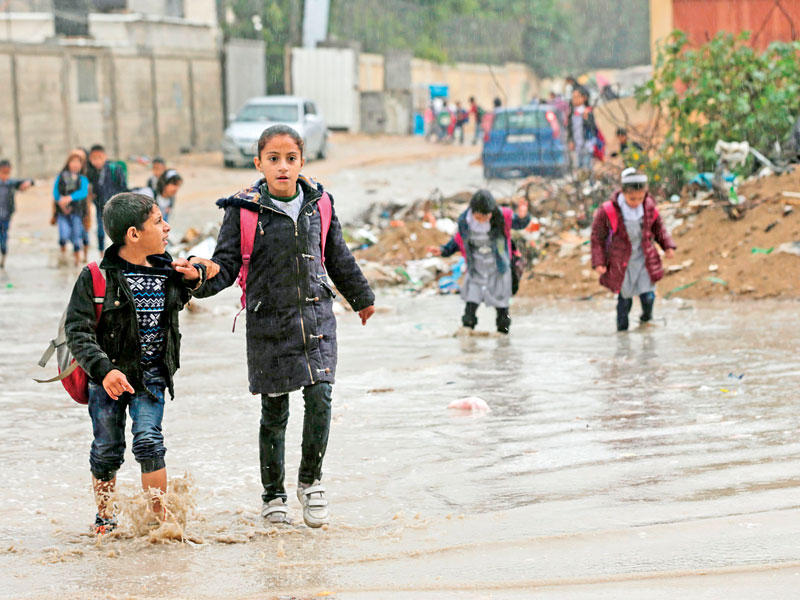 أطفال يسيرون بشارع في قطاع غزة الذي تعرض لأمطار غزيرة أمس الأول (أ ف ب)