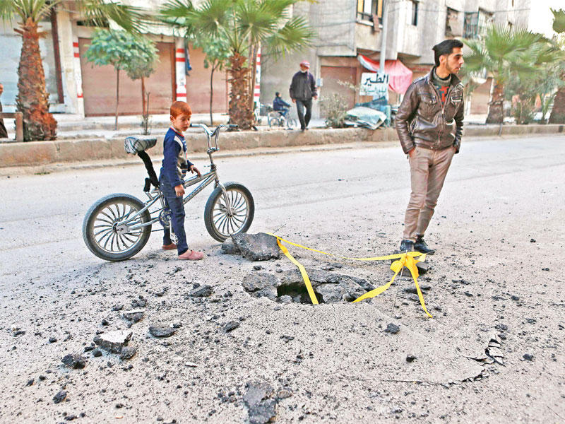 فتى سوري يشاهد موقع سقوط قذيفة هاون في الحمورية بالغوطة الشرقية التي تسيطر عليها المعارضة (أ ف ب)