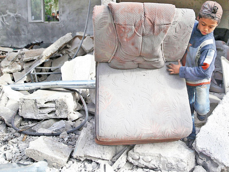 فتى سوري في موقع تعرض لغارة في الغوطة أمس (رويترز)