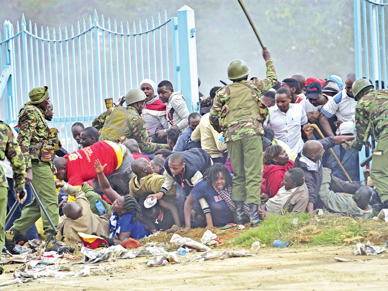 شرطيون كينيون يضربون مؤيدين للرئيس كانوا يريدون الدخول إلى الملعب حيث أدى اليمين أمس (أ ف ب)