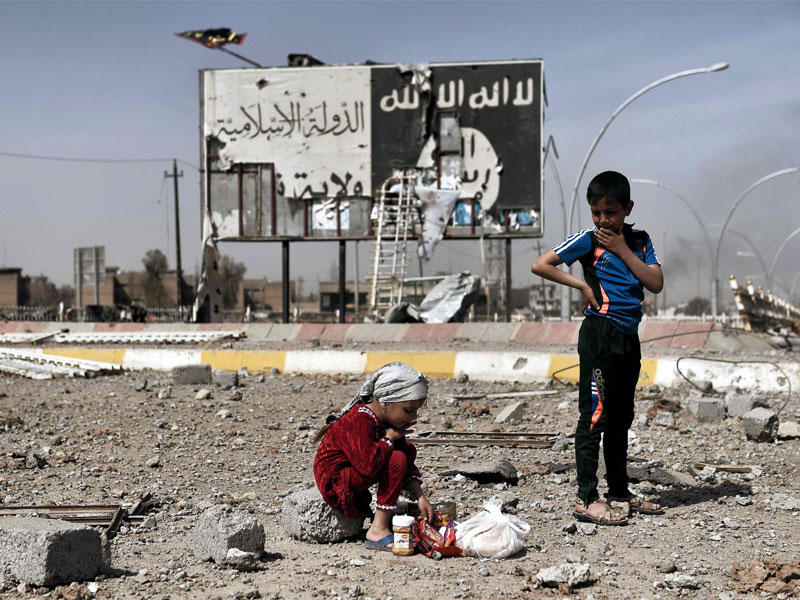 أطفال عراقيون يجلسون وسط أنقاض شارع في حي نابلس الموصل