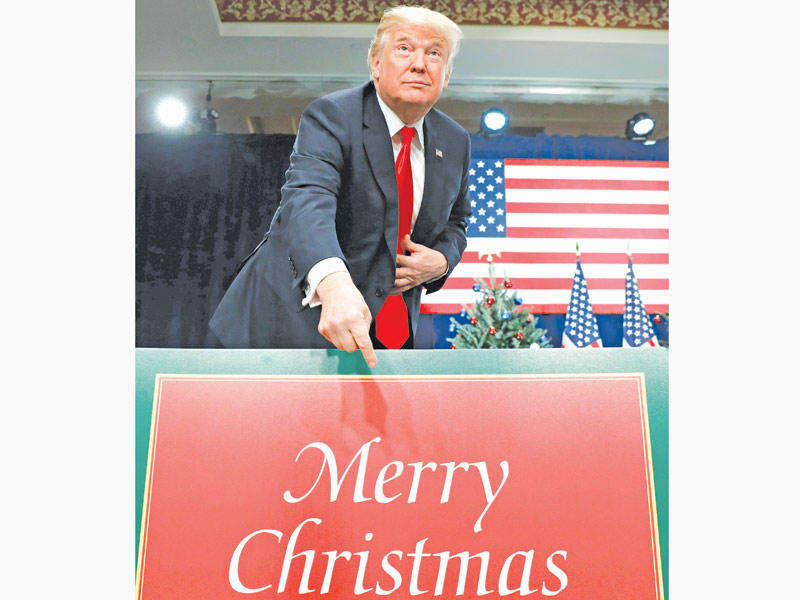 ترامب يشير إلى لافتة معايدة مع اقتراب عيد الميلاد عند المسيحيين في ميزوري أمس الأول (رويترز)