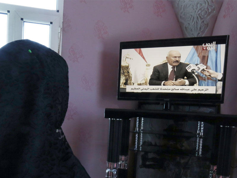 امرأة يمنية تشاهد الرئيس اليمني السابق علي عبد الله صالح يلقي خطابا على تلفزيون اليمن اليمني المؤيد للصالح
