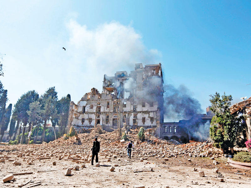 حوثي قرب مبنى بمحيط القصر الرئاسي عقب غارة لمقاتلات التحالف العربي في صنعاء أمس (أ ف ب)