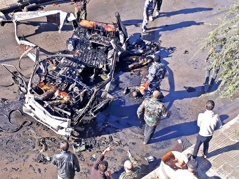 مدنيون وعمال إنقاذ قرب حطام الحافلة في حمص أمس (رويترز)