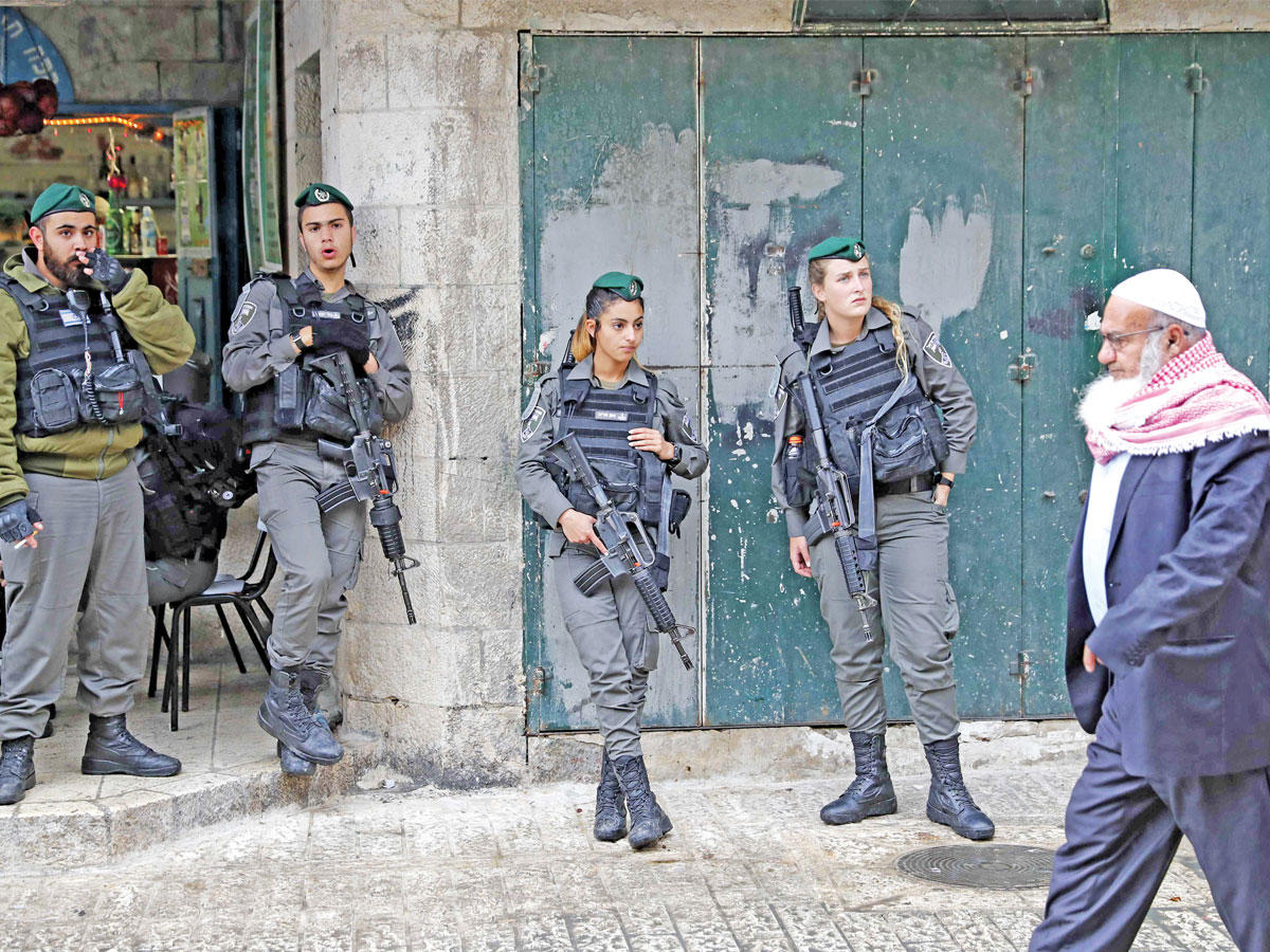 فلسطيني يمر أمام عناصر من حرس الحدود الإسرائيلي قرب باب دمشق في القدس القديمة أمس (أ ف ب)