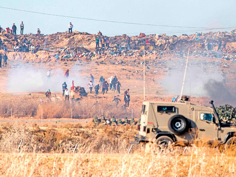 مواجهات بين الفلسطينيين والجيش الإسرائيلي عند الشريط الفاصل في غزة أمس (أ ف ب)