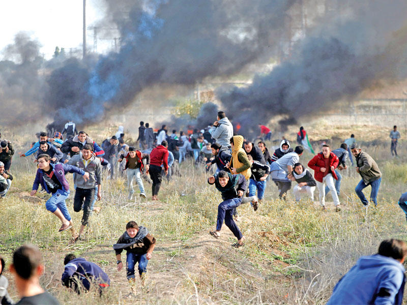 فلسطينيون يهربون من قنابل إسرائيلية على الشريط الحدودي في غزة أمس (رويترز)n