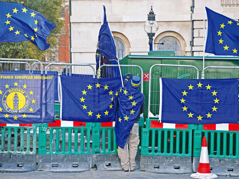 متظاهر مؤيد للاتحاد الأوروبي يعلق علم الاتحاد على سياج البرلمان البريطاني في وستمنستر أمس (أ ف ب)