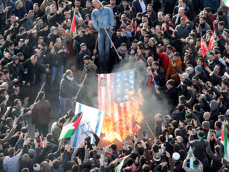 متظاهرون يحرقون علماً أميركياً ومجسماً لترامب بمدينة إسطنبول في تركيا العضو في الناتو أمس (رويترز)