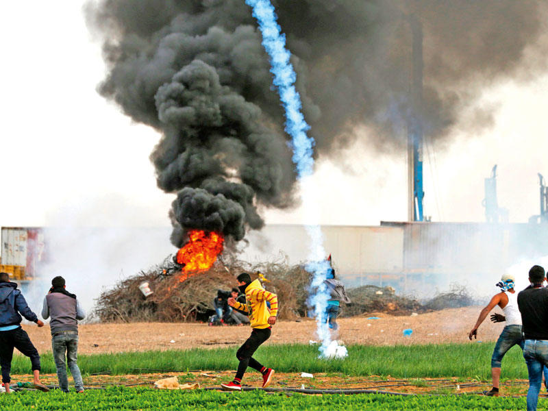مواجهات عبر السياج الحدودي بين فلسطينيين في خان يونس بغزة والجيش الإسرائيلي أمس (أ ف ب)