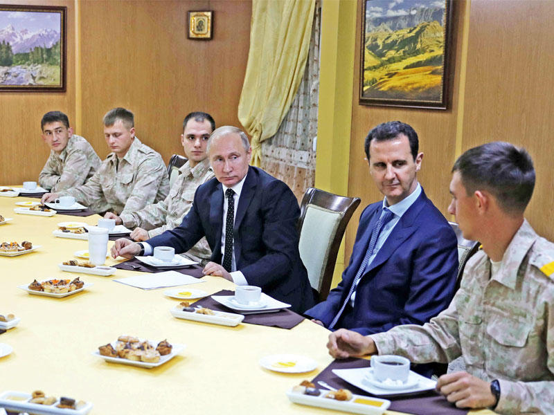 بوتين والأسد يستمعان إلى شرح عسكري في قاعدة حميميم أمس (رويترز)