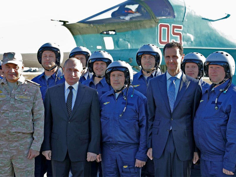 بوتين والأسد بين الطيارين الروس في قاعدة حميميم الجوية في اللاذقية أمس (أ ف ب)n