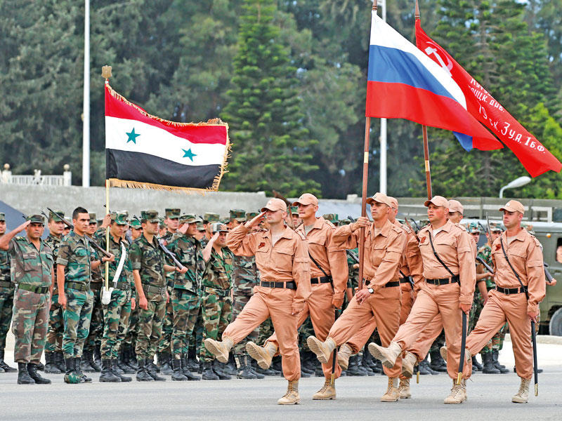 جنود روس وسوريون خلال استعراض عسكري قبل أشهر في قاعدة حميميم الجوية في اللاذقية شمال غرب سورية (أي بي ايه)