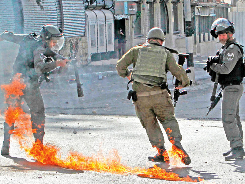  جنود إسرائيليون يحاولون تجنّب زجاجة مولوتوف حارقة خلال مواجهات في بيت لحم أمس (ا ف ب)