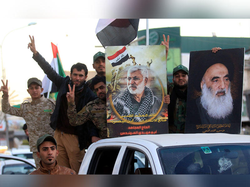 عناصر من الحشد الشعبي يرفعون صور السيستاني وأحد قادتهم أبو مهدي المهندس خلال احتفالات بالانتصار على «داعش» قبل أيام في البصرة (أ ف ب)
