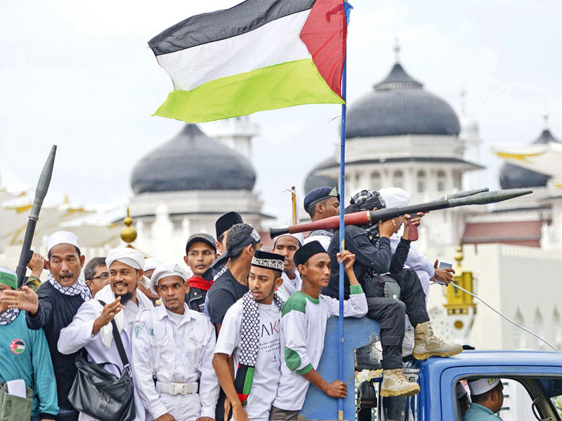 إندونيسيون يحملون أعلاماً فلسطينية ومجسمات اسلحة خلال تظاهرة ضد قرار ترامب أمس (أ ف ب)