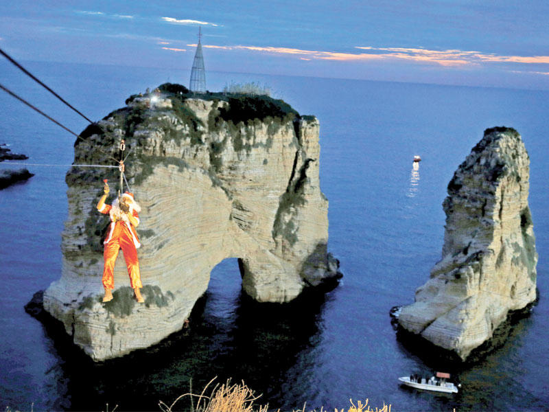 لبناني يرتدي ثياب سانتا كلوز ينزلق على حبل إلى صخرة الروشة لإضاءة شجرة عيد  الميلاد مساء أمس الأول (رويترز)