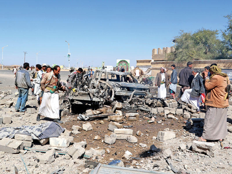 حوثيون حول سيارة استهدفتها مقاتلات التحالف في صعدة معقل المتمردين شمال اليمن أمس            (رويترز)