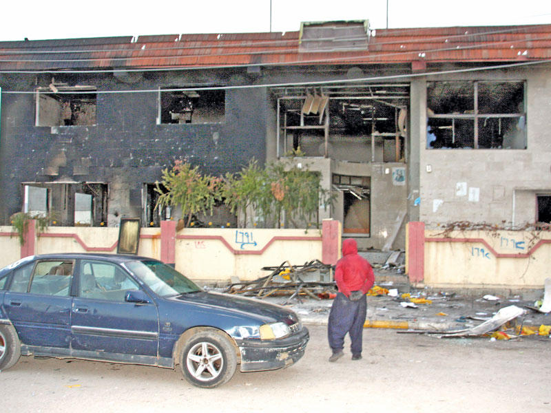 رجل يتفقد أمس مقراً حزبياً تعرض للحرق في إقليم كردستان  (أ ف  ب)