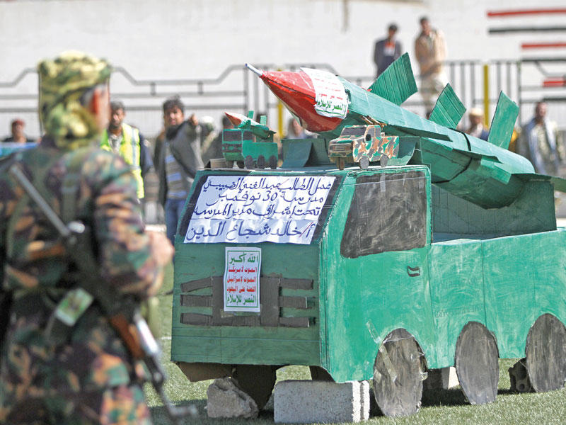 مسلحون حوثيون ومجسم لشاحنة تحمل صاروخاً خلال استعراض في صنعاء أمس (رويترز)