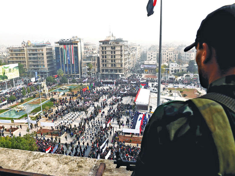 جندي سوري يشاهد عرضاً عسكرياً اقيم في حلب أمس الأول بمناسبة مرور عام على استعادة النظام للمدينة (أ ف ب)